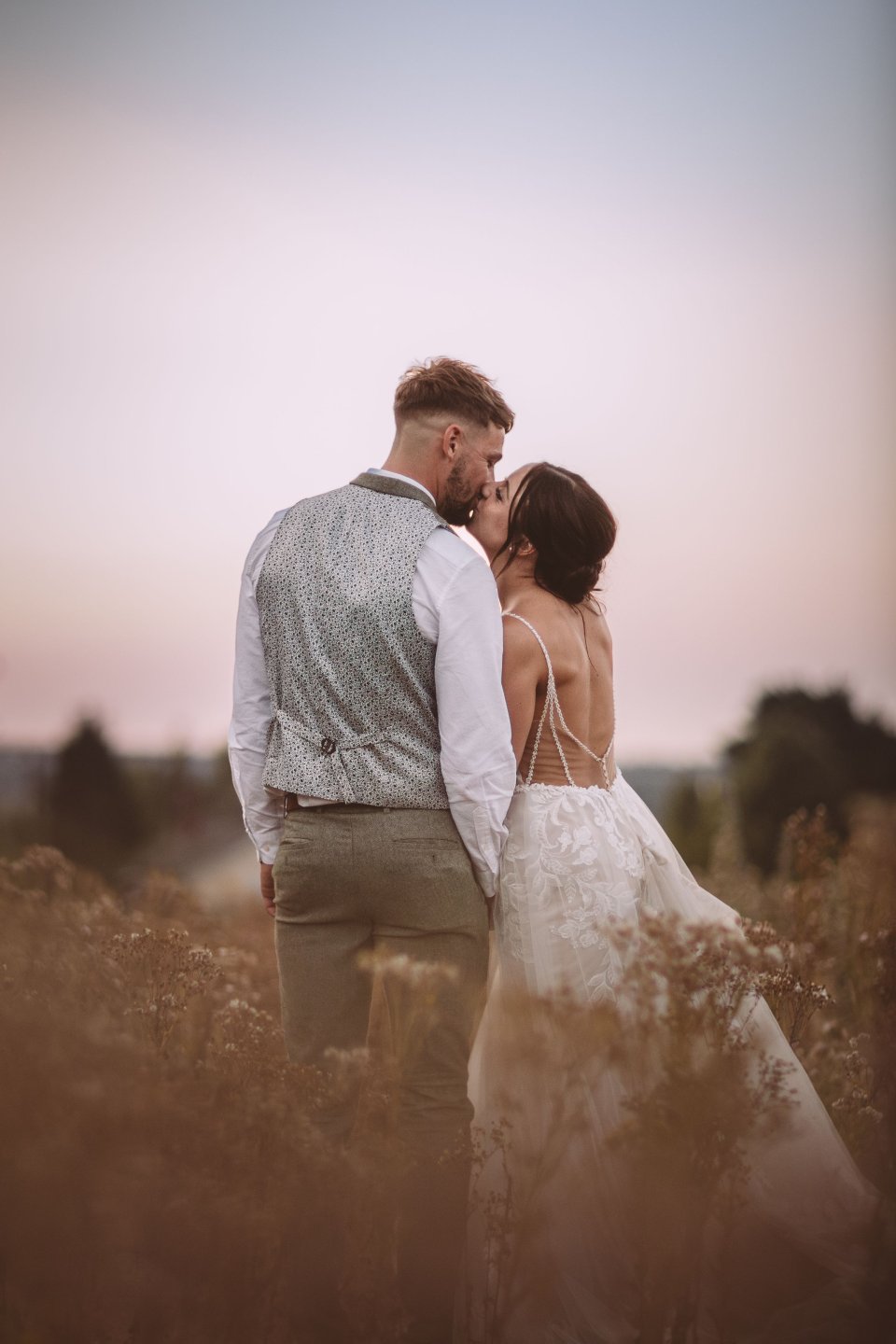 A couple shares an intimate moment at their Suffolk Wedding in a golden field sunset.
