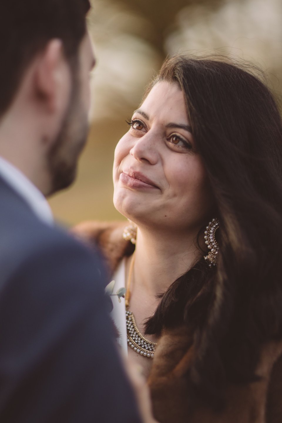 A close up photograph of a bride looking up at her groom with an emotional smile outside Hintlesham Hall