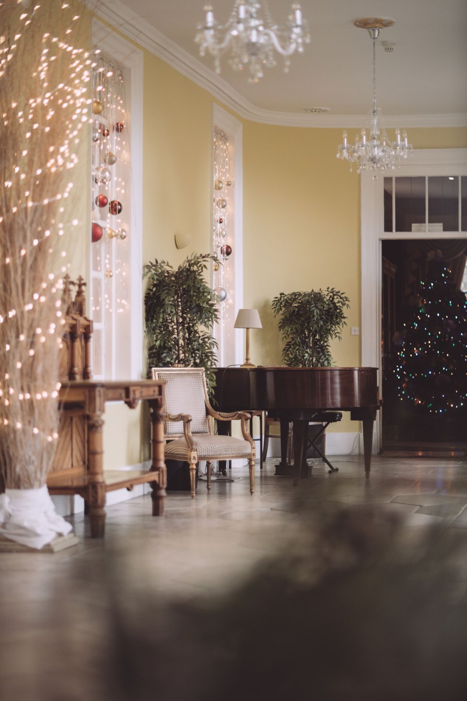 A grand piano and an ornate armchair in the corridor of Suffolk Wedding Venue Hintlesham Hall