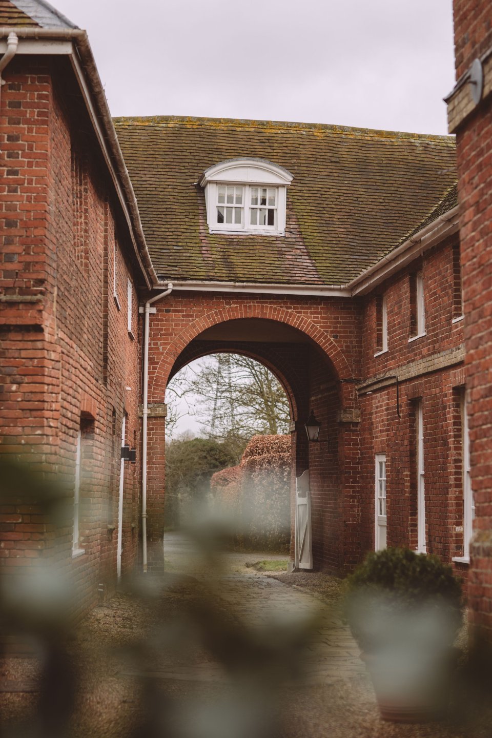 An exterior brick archway adjoining two wings of Suffolk wedding venue Hintlesham Hall