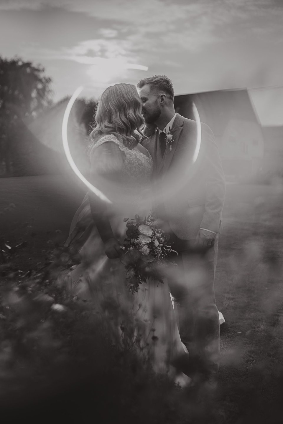 A suffolk bride and groom kiss with a ring of light surrounding their heads