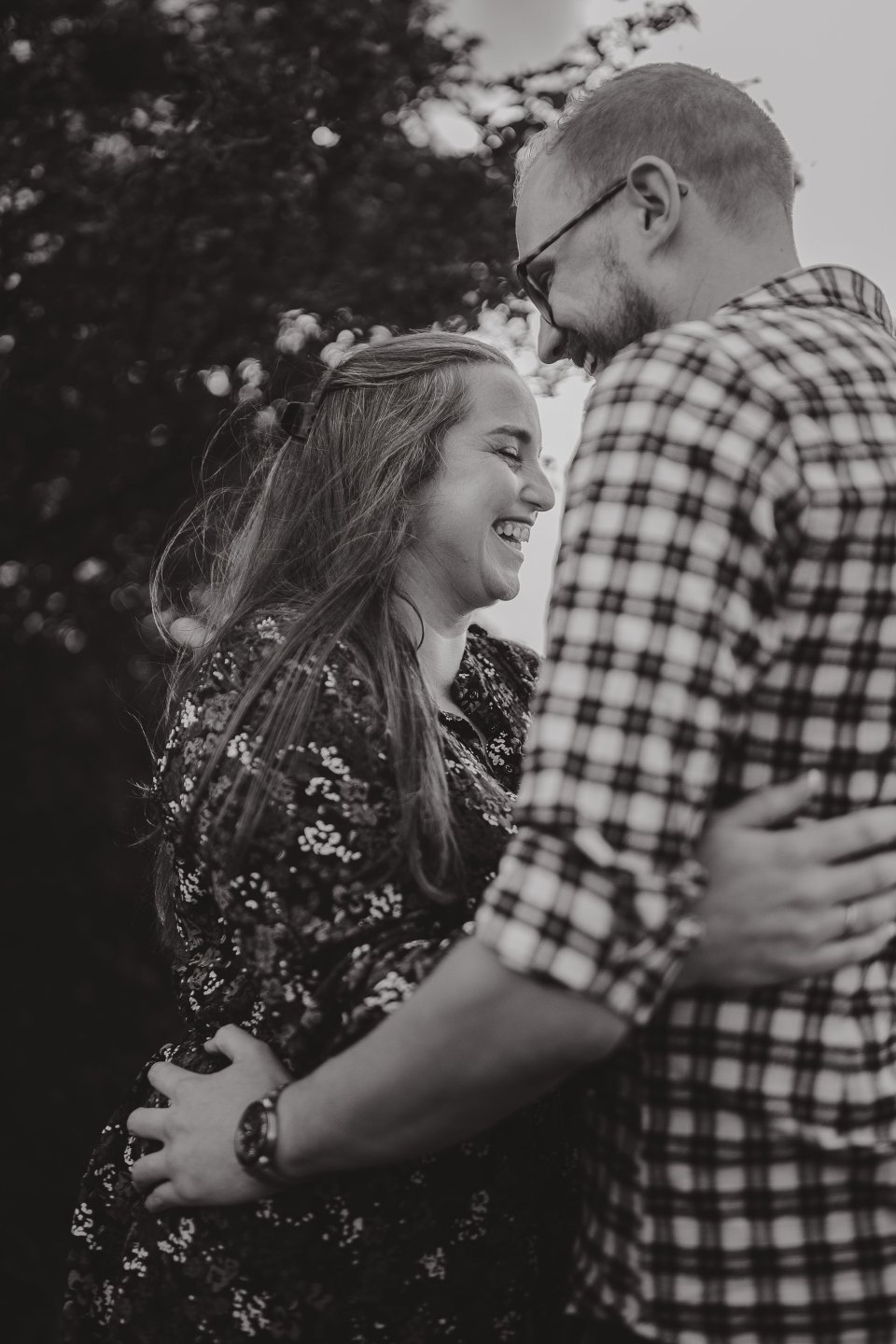 A couple embracing and laughing together outdoors in black and white.