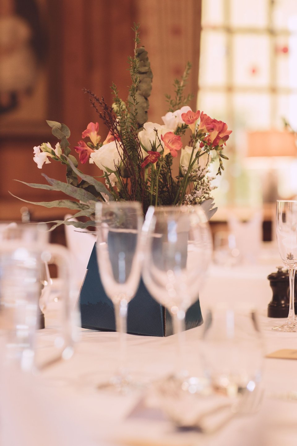 Glasses in front of a flower centrepiece on a table at a Hintlesham Hall wedding in Suffolk