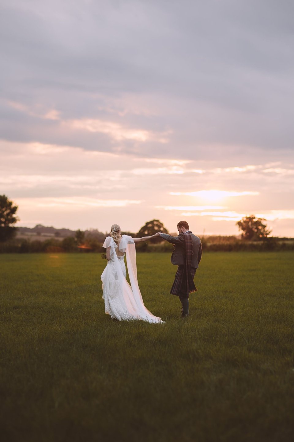 A bride and groom dance at sunset in the suffolk countryside