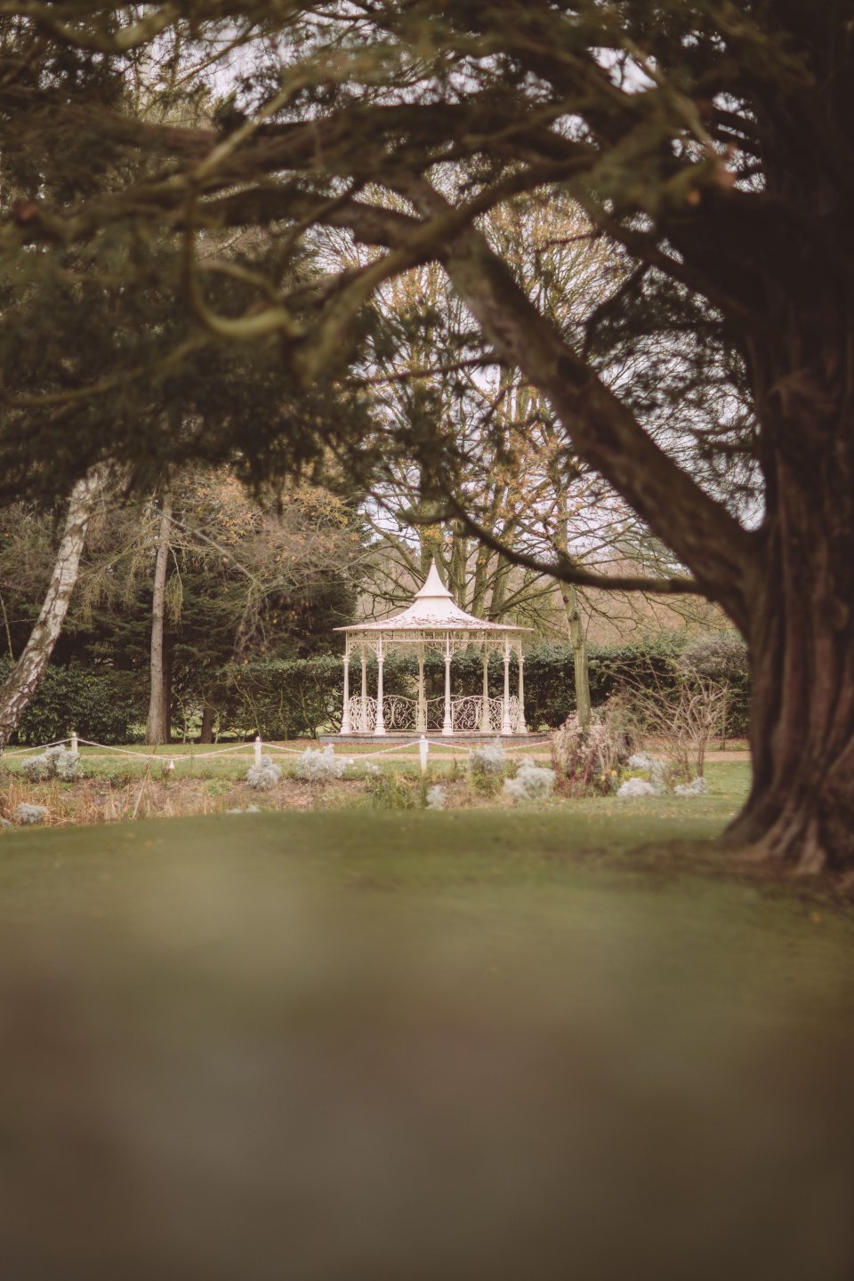 Small bandstand in with an overhanging tree in the foreground in the back of Suffolk wedding venue Hintlesham Hall