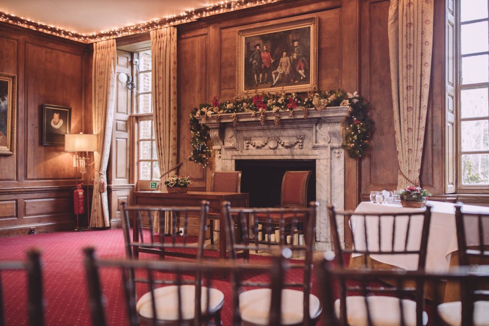 Suffolk wedding ceremony room at Hintlesham Hall with wood panelled walls, wooden chairs and an ornate fireplace