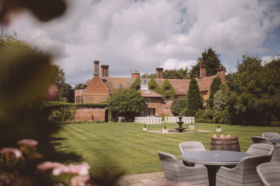 Suffolk wedding venue ready for outdoor ceremony with manicured lawn, foliage and patio furniture in the foreground