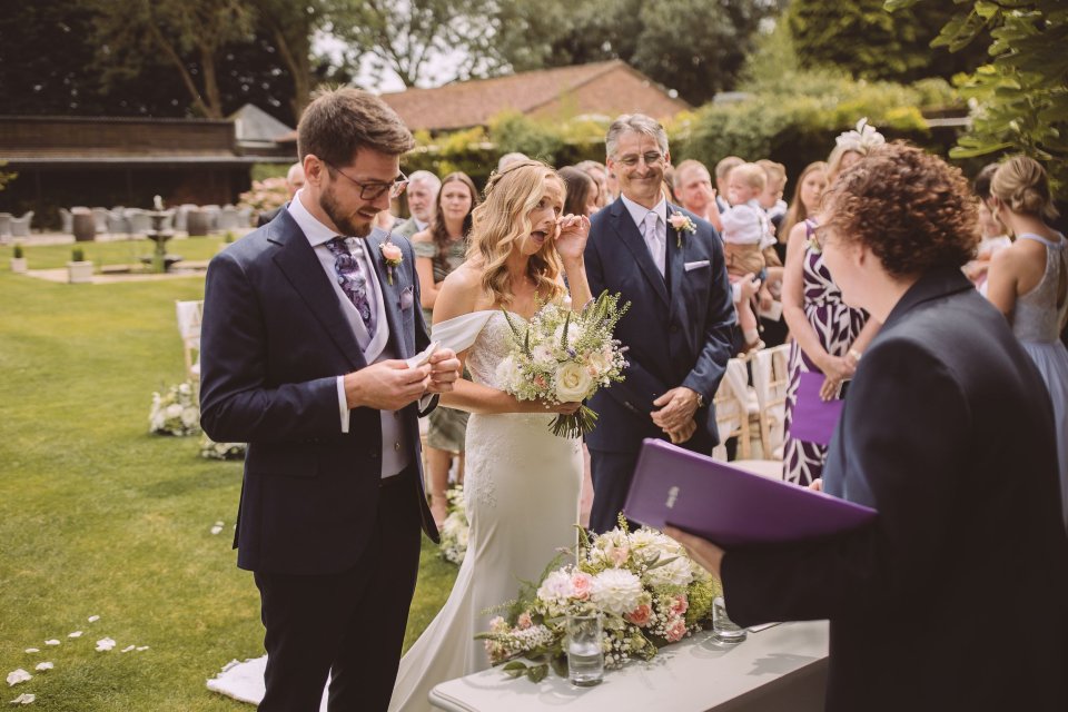 Couple participates in wedding ceremony rituals outdoors with guests looking on.