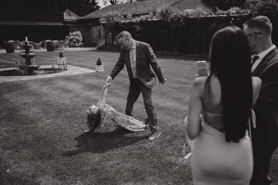 A candid black and white photo of guests interacting on a lawn at an outdoor event.