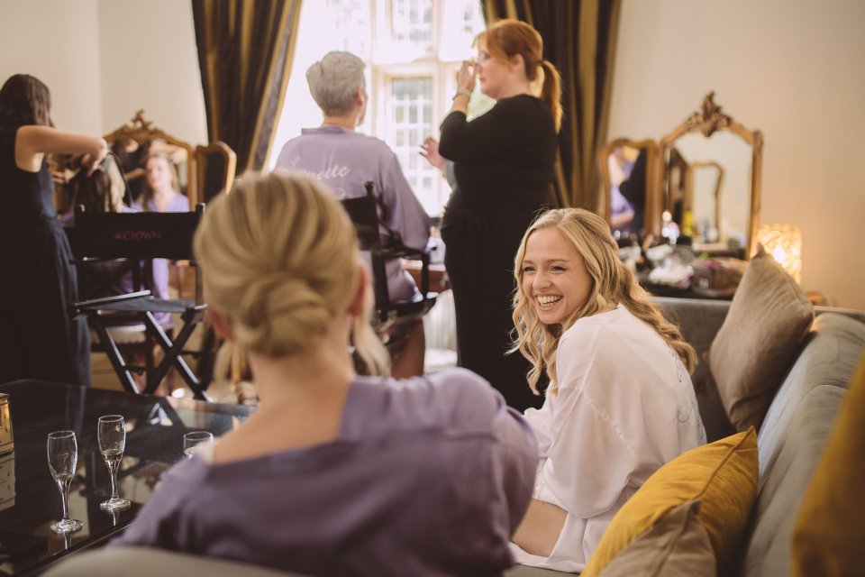 A suffolk bride laughs with her bridesmaid whilst getting ready for her wedding