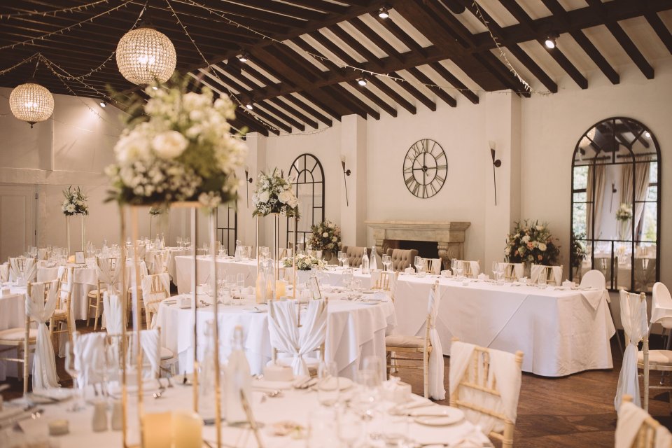 Wedding reception room decorated with white tables, lanterns and floral centerpieces.