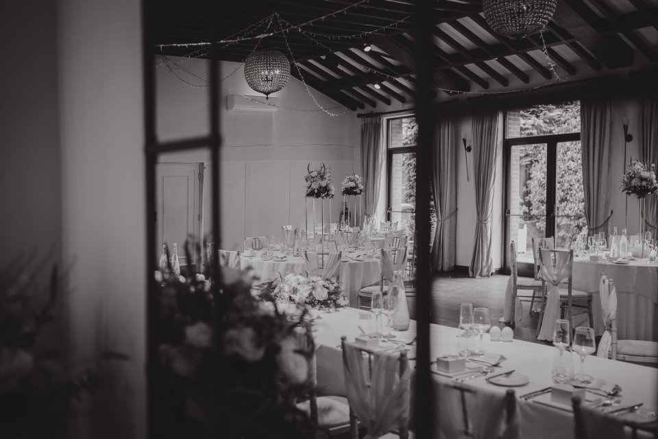 Black and white view of an elegant wedding reception room setup with round tables reflected in a mirror