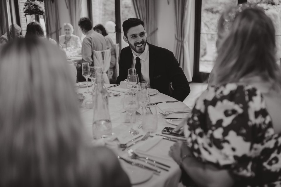 Black and white photo of wedding guests conversing at an elegant dinner setting.