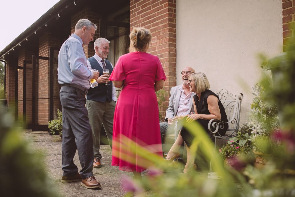 Suffolk Wedding guests gathered outside a brick building in a garden.