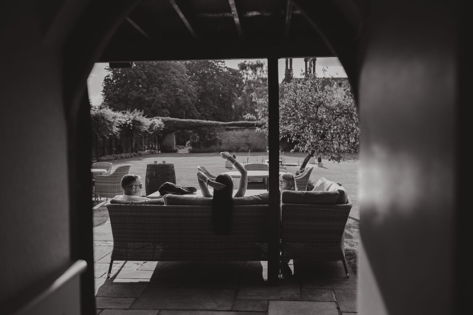 Black and white photo showing silhouettes through an archway overlooking an outdoor seating area.