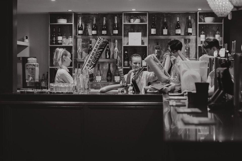 Black and white image of a bar interior and young staff blowing up a variety of inflatables